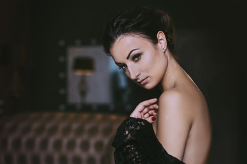 Seductive brunette woman with bare pillows sits on expencive luxury sofa 