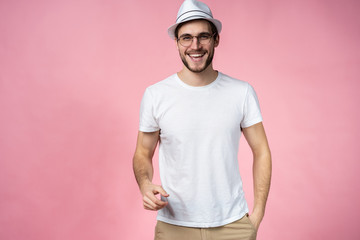 Cheerful hipster guy smiles happily, has excited expression, dresssed casually isolated over pink studio background. People, youth, emotions concept.