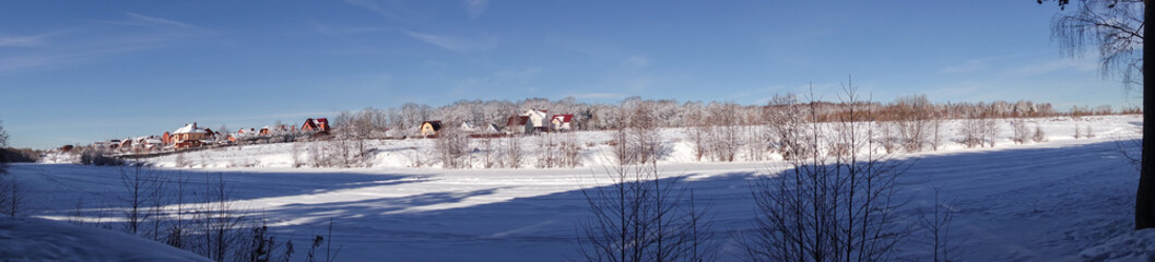 Paranoma winter landscape. Village near the forest in winter in the snow. Sunny frosty day