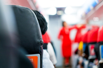men in plane seat looks at the airhostess explain at the front of the row.