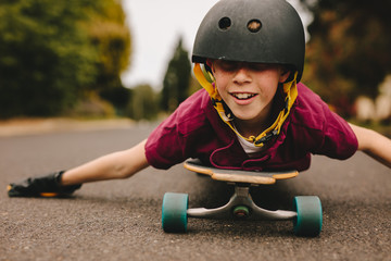 Funny boy with helmet lying on skateboard © Jacob Lund
