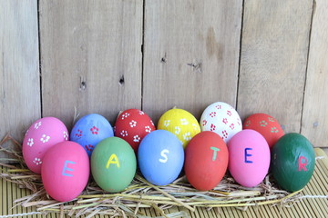 colorful easter eggs in basket on wooden background