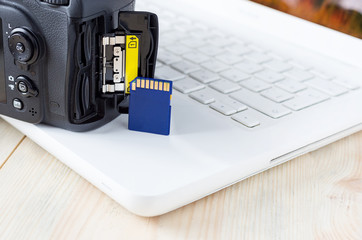 flash card in hand on camera and laptop background, memory card for SLR camera, flash drive, photo...