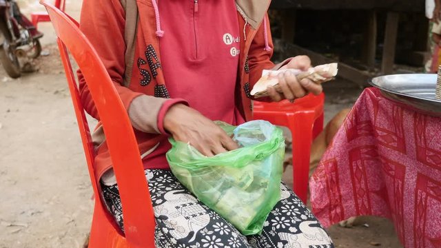 seller clams counts his money, she has made for the day, at a market in rural area ( close up)