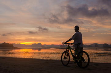 Fototapeta na wymiar Silhouette of a man and bicycle on beach