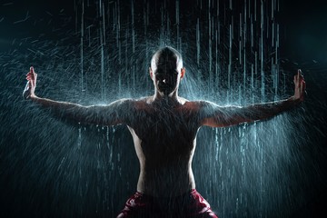 Shirtless qigong gymnast under the rain