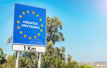 Road sign on the border of a European Union country, Croatia 1km ahead with blue sky copy space - obrazy, fototapety, plakaty