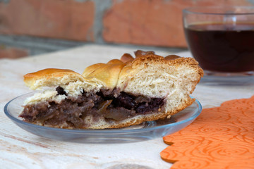 a piece of cake stuffed with apple jam cherries and walnuts and a cup of tea are on the table