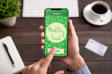 Male hand holding phone with app delivery food on screen