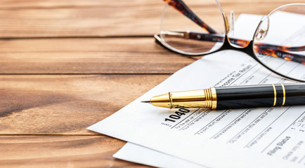 Tax form with pen and glasses on the office desk. Space for text.