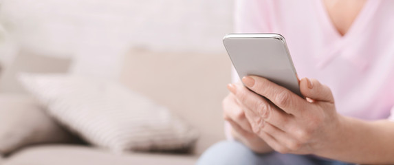 Cheerful aged woman using her smartphone at home