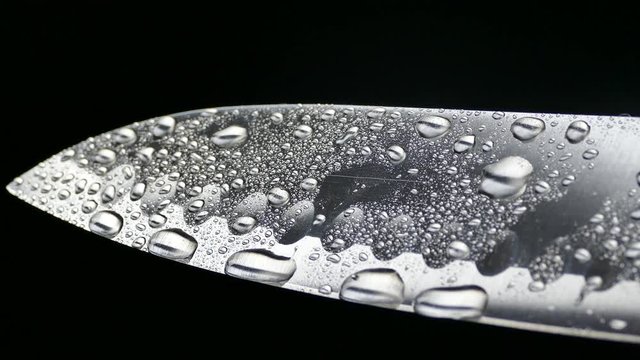 Chef's knife close-up. Knife santoku. blade blade. Drops of water flow down the blade of a knife. Cut vegetables. Cook lunch. Reflection of cold weapons.