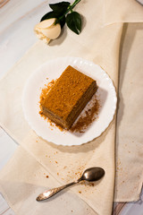 piece of honey cake on a white plate and light background