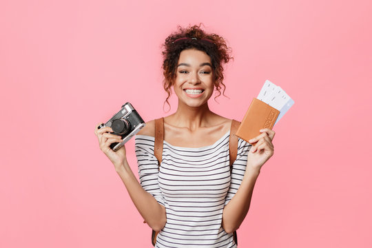 African-american woman holding camera and passport with tickets