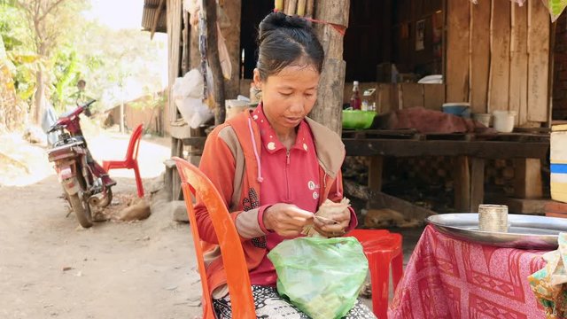 seller clams counts his money, she has made for the day, at a market in rural area