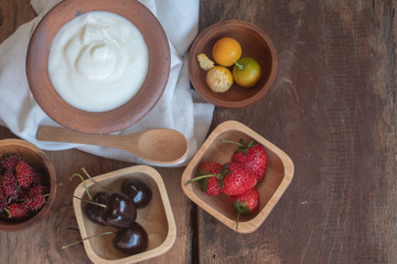 Obraz na płótnie Canvas Natural homemade plain organic yogurt mixed with fresh berry fruit white bowl and wood spoon on wood texture background