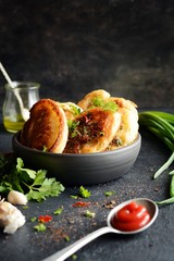 Homemade savory pancakes with minced meat pieces, dill, parsley and green onions, garlic, tomato sauce and chili peppers on a dark background. Snack option pancakes. Fritters with minced meat