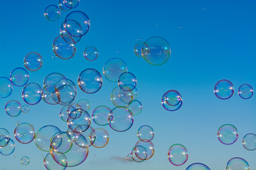 Many soap bubbles in air, blue sky, outdoor fun for everybody