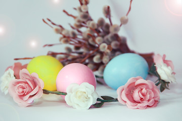 pink yellow blue eggs against a background of willow and flowers for the Easter holiday