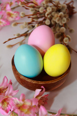 pink yellow blue eggs against a background of willow and flowers for the Easter holiday