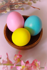 pink yellow blue eggs against a background of willow and flowers for the Easter holiday