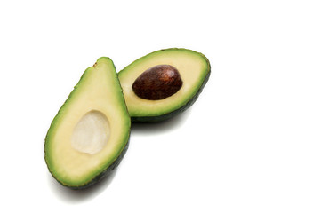 green avocado cut in half lying on a white background