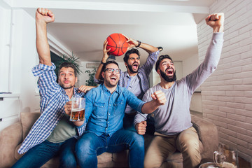 Happy friends or basketball fans watching basketball game on tv and celebrating victory at home.Friendship, sports and entertainment concept.