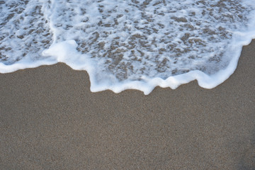 White wave foam wipes sands beach