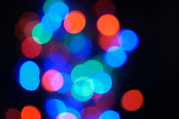 Multi-color blue holiday garland. Garland is blurred. Many big colorful round lights. Fully defocused photo. Blurred background and foreground. Holiday mood. New Year and Christmas is coming.