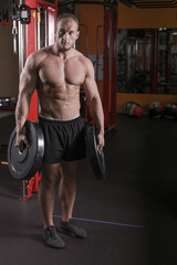 Fototapeta na wymiar a man is engaged in bodybuilding in the gym, raises the bar and trains his muscles.