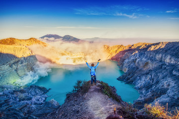 The tourists raised their hands to express their joy over Kawah Ijen volcano for Beautiful sanrise of  landscape view in Indonesia.