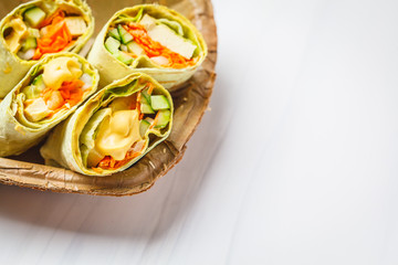Vegan tofu wraps with cashew cheese sauce and vegetables, white background.
