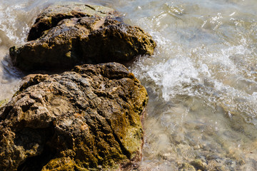 wet, colored stones - brownish-green, yellowish; one stone highlighted with sharpness and light;