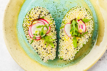 Beautiful avocado with sesame, arugula, radish and green onions. Healthy vegan food concept. © vaaseenaa