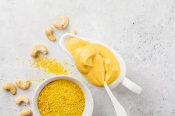 Vegan Cashew Cheese Sauce in white sauceboat, white background, top view.