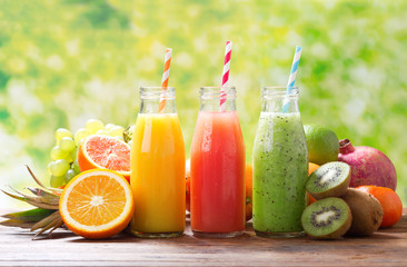 bottles of fruit juice and smoothie with fresh fruits
