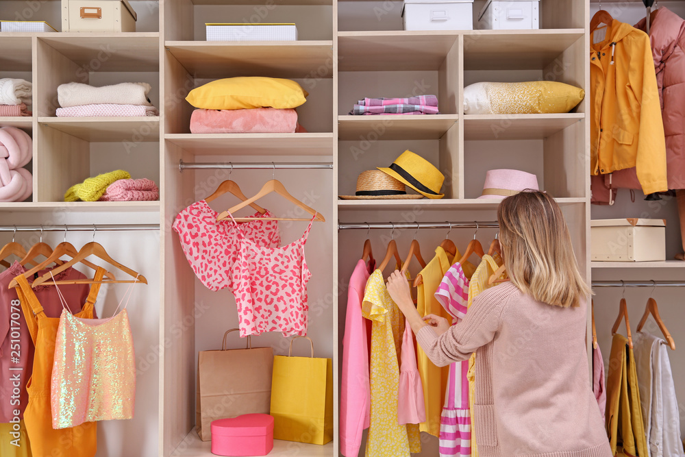 Wall mural Woman choosing clothes from large wardrobe closet