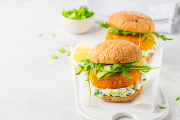 Fish burger with cucumber, arugula and mayonnaise sauce, white background, copy space.
