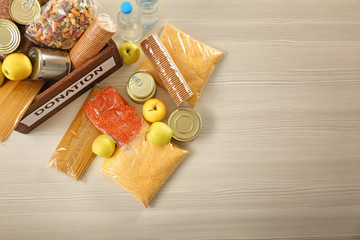 Donation box and different products on wooden table, top view. Space for text