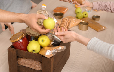 Volunteers taking food out of donation box on table, closeup