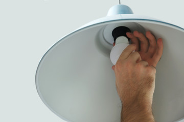 Man changing light bulb in lamp on white background, closeup