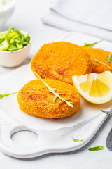Cooked salmon fish cutlets on white board.