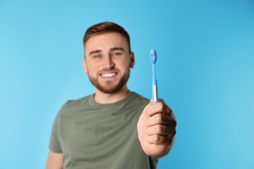 Young man with brush and toothpaste on color background, space for text. Teeth care