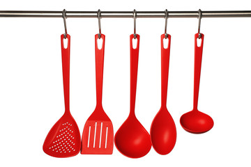Set of kitchen utensils hanging against white background