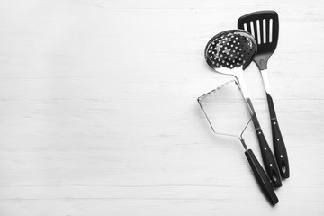 Different kitchen utensils on wooden background, top view with space for text