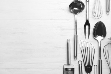 Different kitchen utensils on wooden background, top view with space for text
