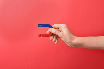 Woman holding magnet on color background, closeup. Space for text