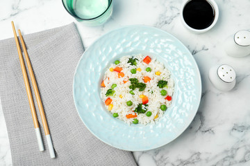 Boiled rice with vegetables served on marble table, flat lay