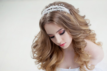 Fototapeta premium Charming young bride with luxury hairstyle. Beautiful woman in wedding dress. Hairstyle with fluffy curls.