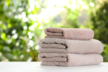 Stack of clean soft towels on table against blurred background. Space for text
